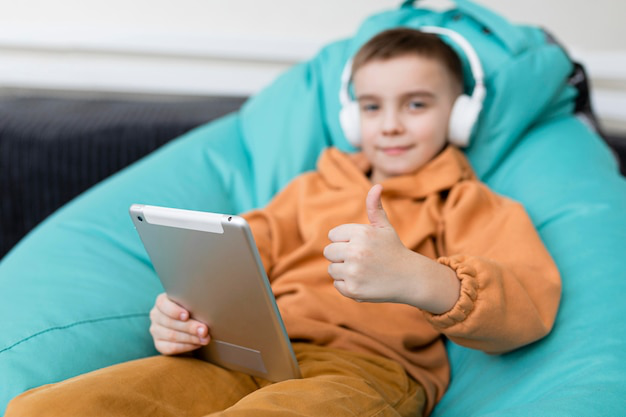 a boy with headphones enjoying time on a tablet